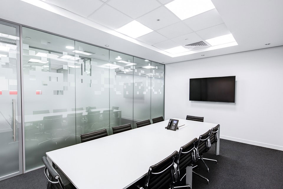 Office boardroom with a wall-mounted display and a conference phone on the table