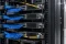 Four stackable network switches in a server rack linked by stacking cables, with fiber uplinks on the top and bottom members