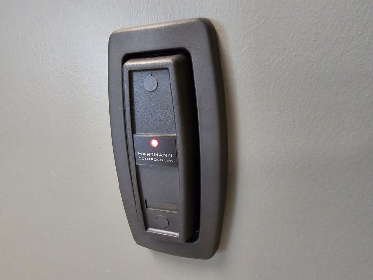 Access control card reader mounted on a wall beside a door