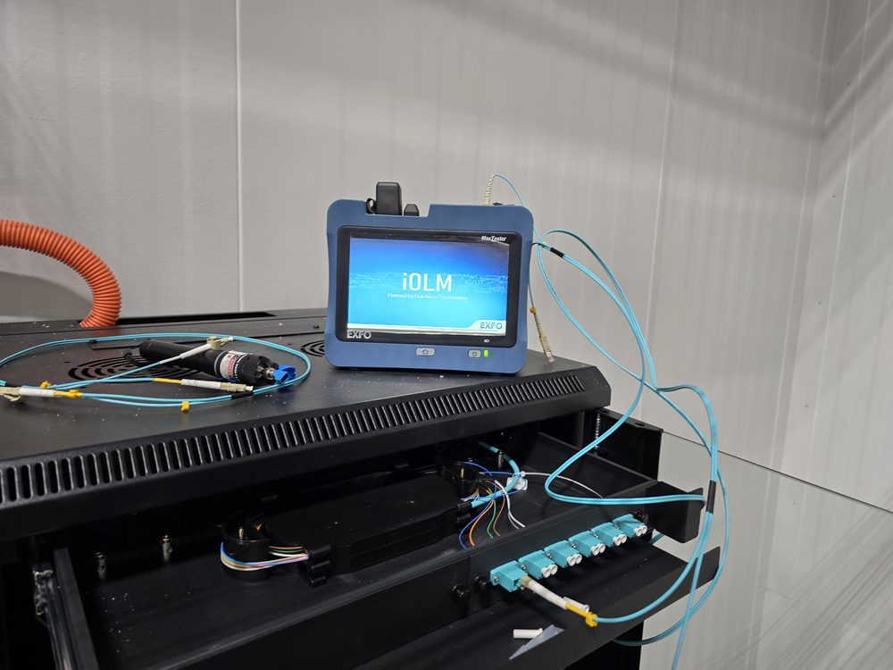 Fiber tester connected to a rack-mounted fiber panel during backbone testing