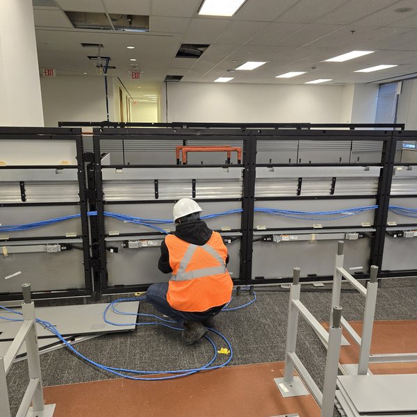 Cablify technician pulling Cat6 network cable at office workstation frames