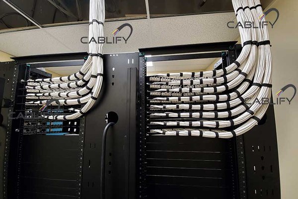 Server room racks with white cable looms dressed into Panduit patch panels