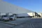 Box trucks and a tractor-trailer backed into dock doors along a large warehouse wall
